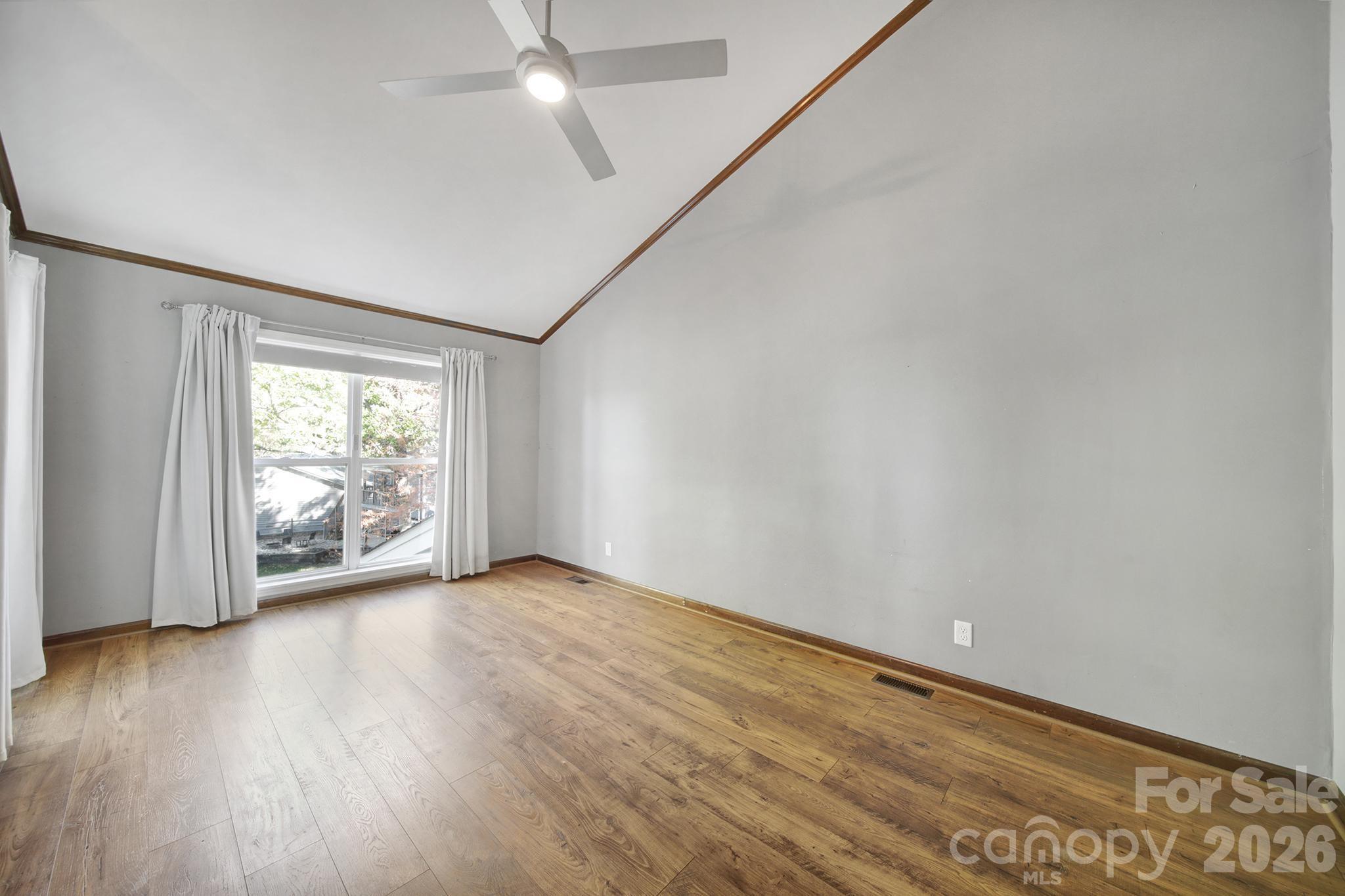 7005 Tega Cay Drive Tega Cay, SC 29708 - Photo 22 of 48 an empty room with wooden floor and windows with curtains