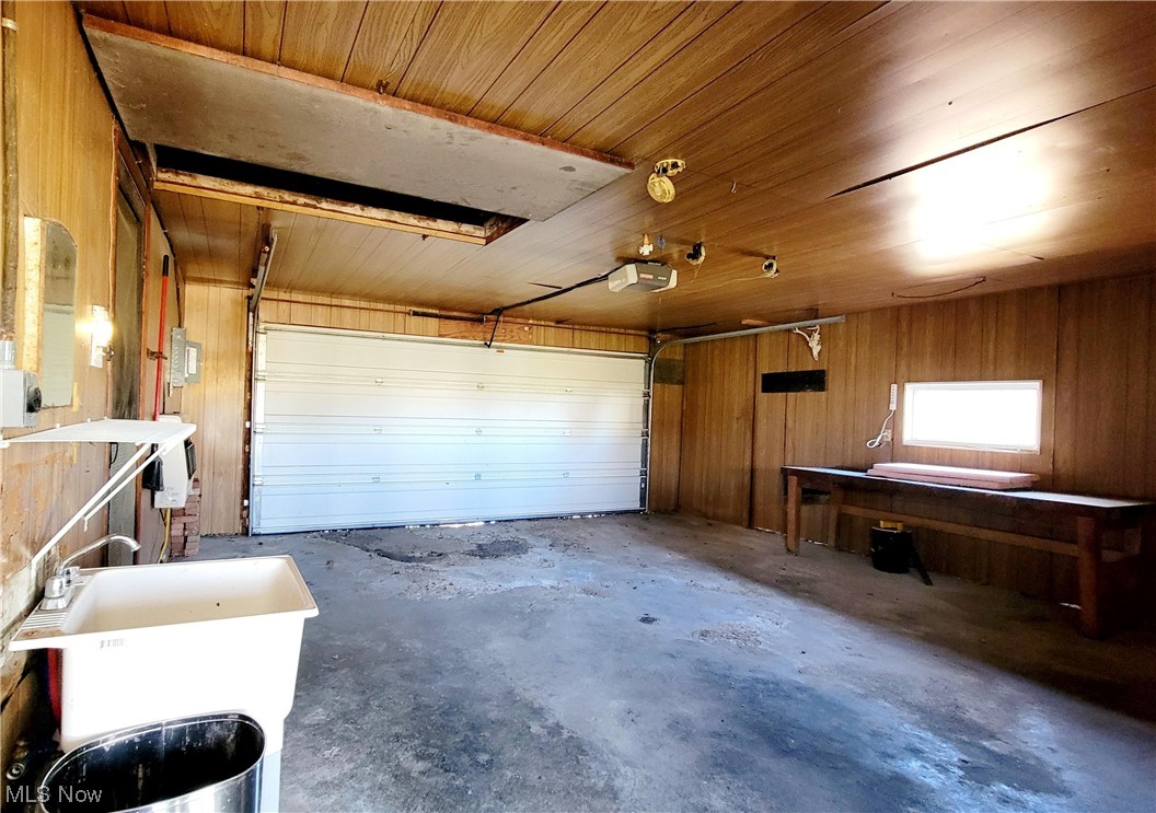 405 Bryan Road Milan, OH 44846 - Photo 20 of 35 Garage with wooden ceiling, wood walls, and a garage door opener