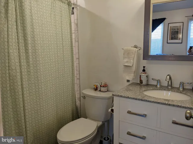 a bathroom with a granite countertop sink toilet and mirror