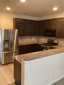 a view of kitchen with stainless steel appliances wooden cabinets and a refrigerator