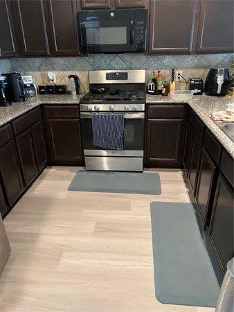 a kitchen with stainless steel appliances granite countertop a stove a sink and a microwave