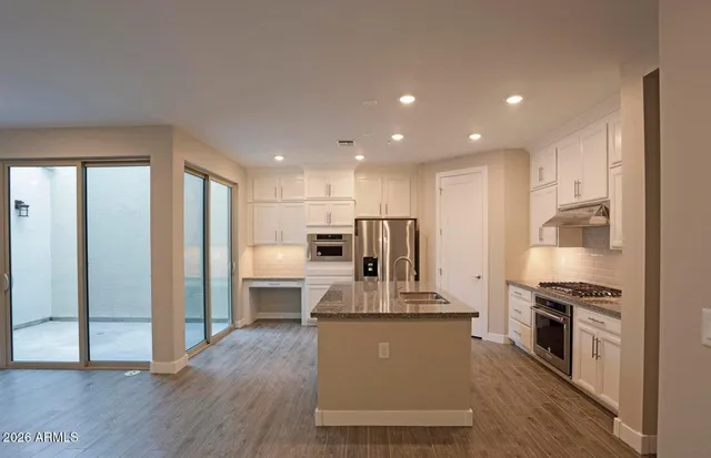 a kitchen with kitchen island a counter top space a refrigerator a stove a sink and a cabinets