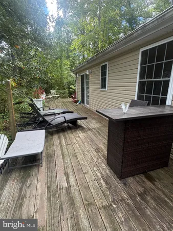 a view of house with deck outdoor seating and trees in the background