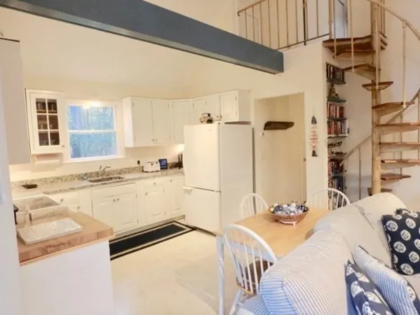 a kitchen with a sink a stove a refrigerator and white cabinets with wooden floor