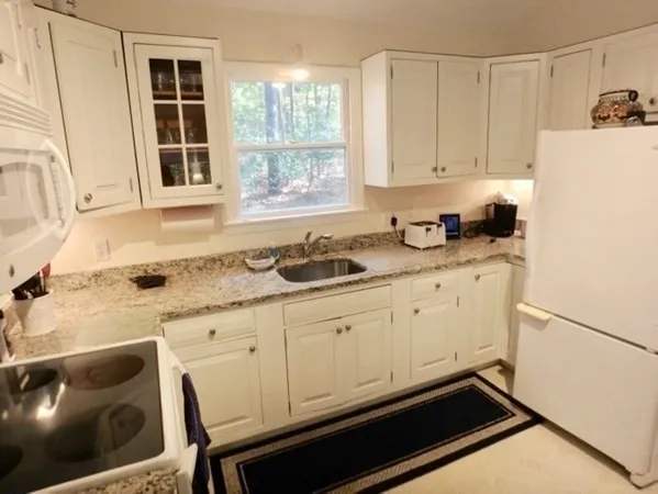 a kitchen with granite countertop white cabinets and white appliances