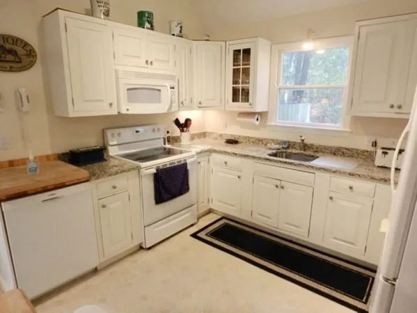 a kitchen with granite countertop white cabinets and white appliances