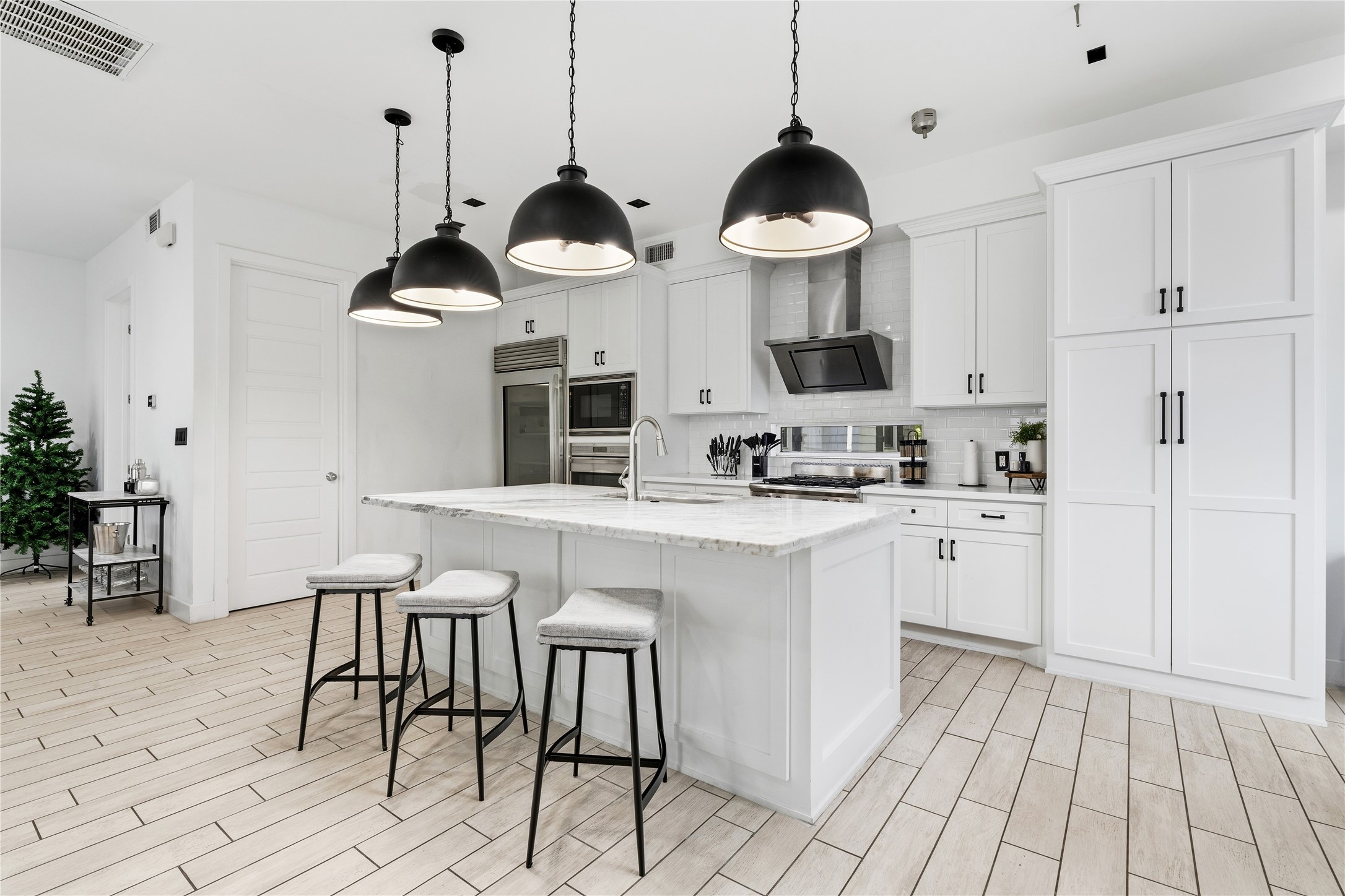 2025 Colquitt Street, Unit A Houston, TX 77098 - Photo 11 of 40 a kitchen with stainless steel appliances a stove a sink and chairs with wooden floor