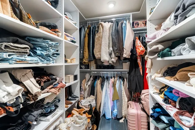 a view of walk in closet with clothes and shoes