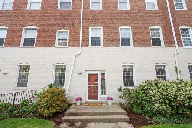 a front view of a building with garden and entryway