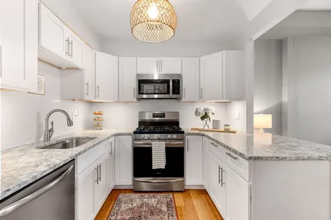 a kitchen with granite countertop a sink a stove top oven a counter space and cabinets