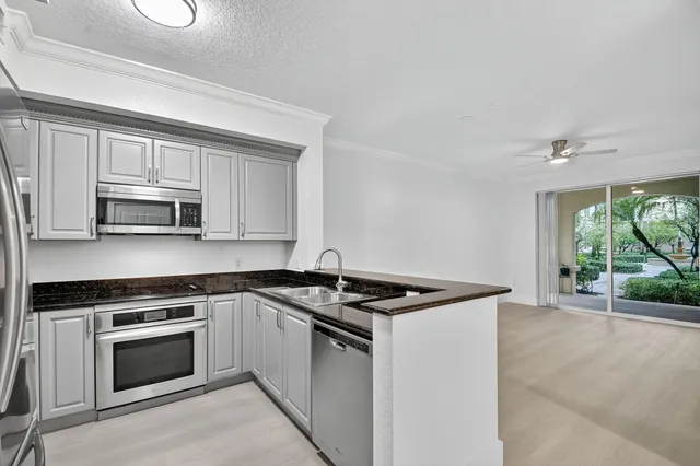 a white kitchen with granite top and stainless steel appliances