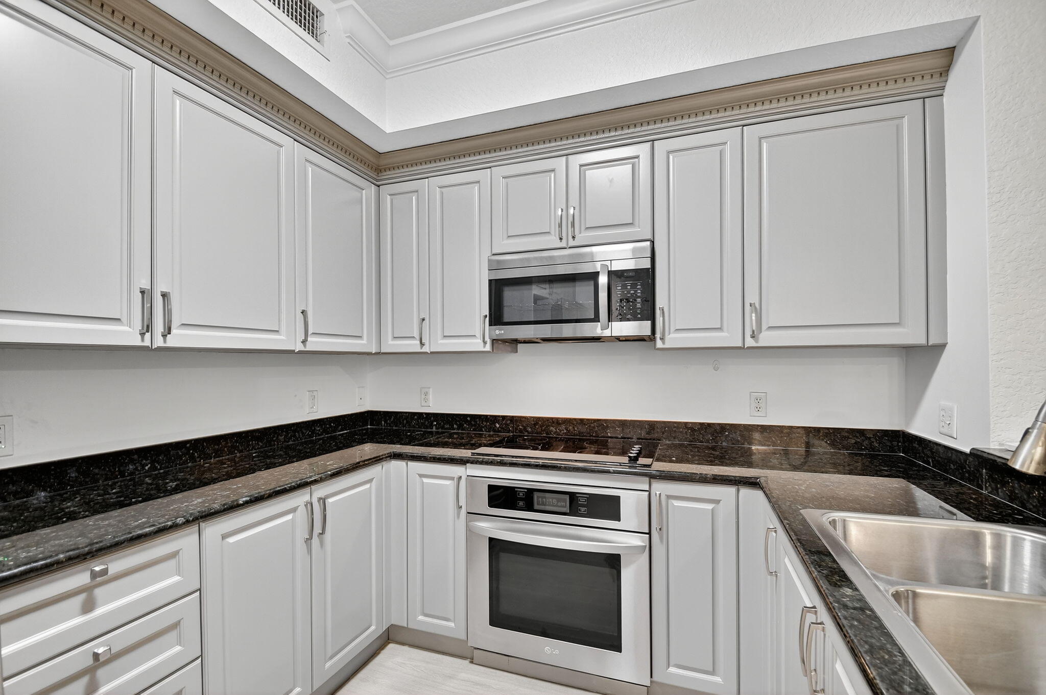 1 Renaissance Way, Unit 116 Boynton Beach, FL 33426 - Photo 6 of 34 a white kitchen with granite top and stainless steel appliances