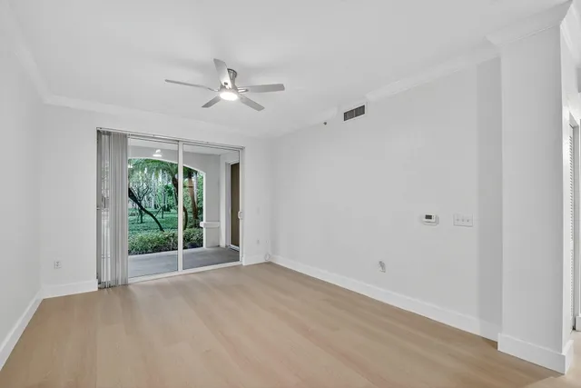 a view of empty room with wooden floor and ceiling fan