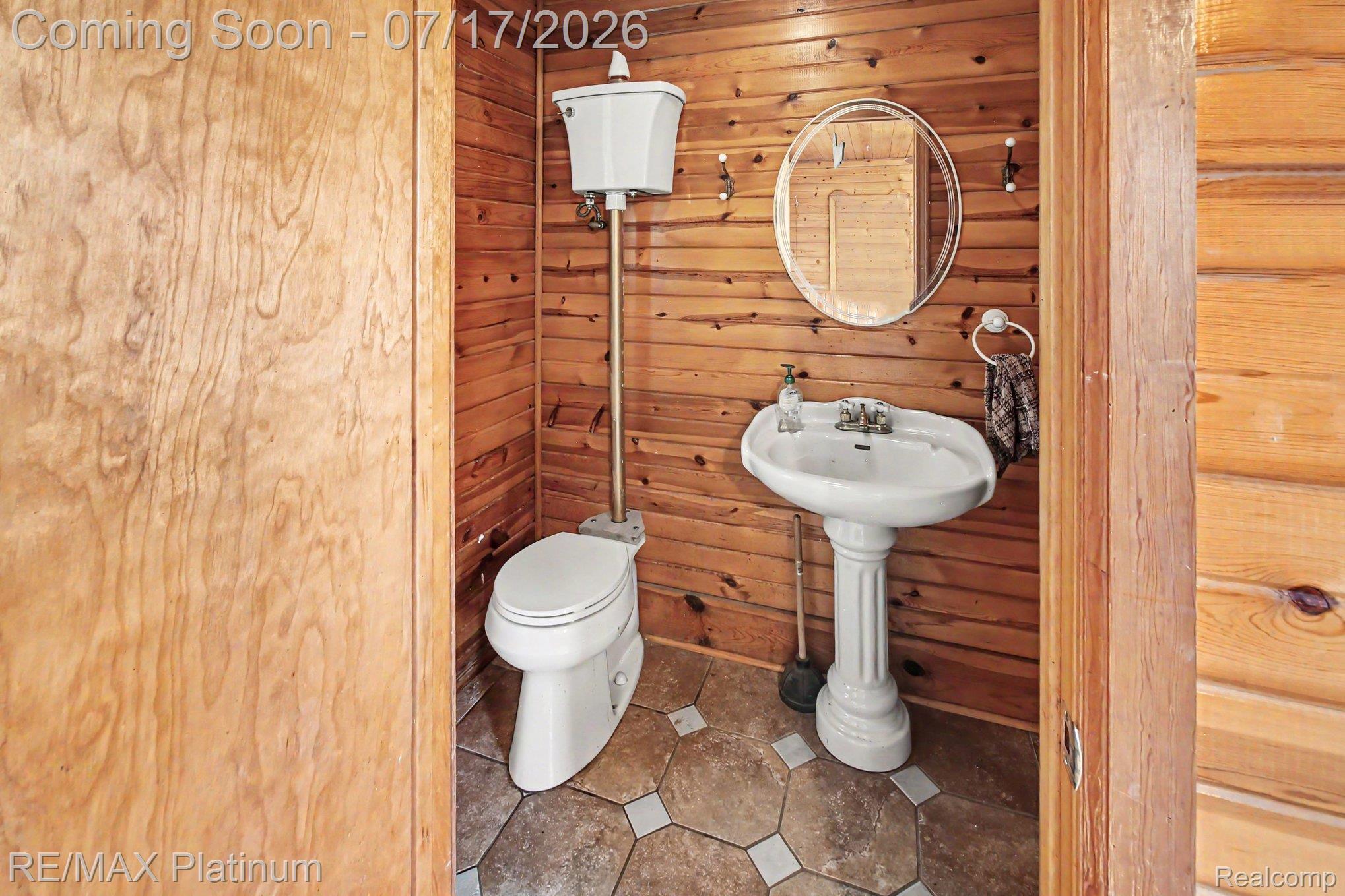4205 Musson Road Howell, MI 48855 - Photo 12 of 23 Powder room featuring wood plank wall paneling, a pedestal sink, and a high-tank toilet