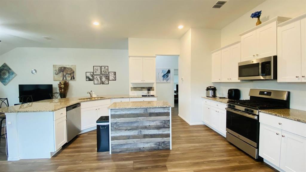 4612 Azurite Road Little Elm, TX 76227 - Photo 3 of 11 a kitchen with stainless steel appliances a stove top oven a sink a refrigerator white cabinets and wooden floor