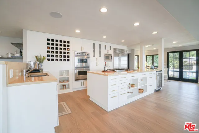 a large white kitchen with kitchen island a sink stainless steel appliances and cabinets