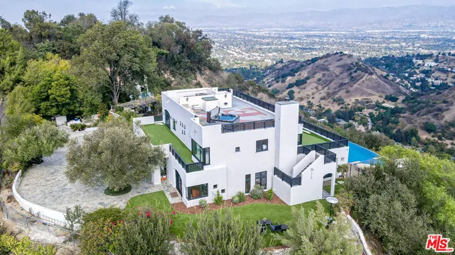 an aerial view of a house with a yard and large tree