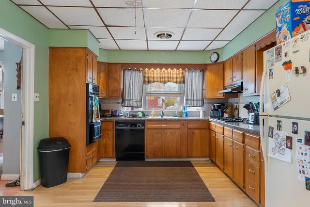 a kitchen with stainless steel appliances granite countertop a refrigerator a sink dishwasher a stove and white countertops with wooden floor