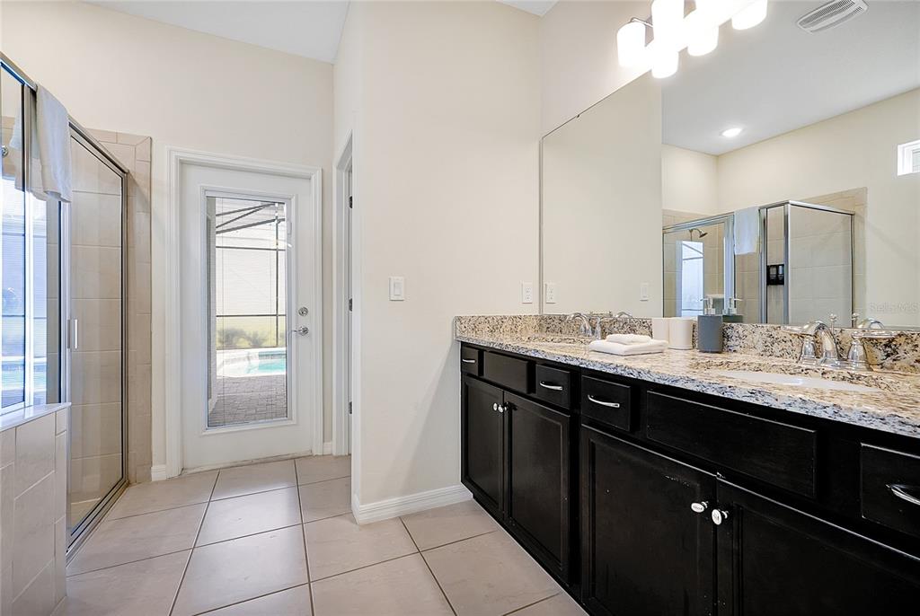 4494 Kaipo Road Davenport, FL 33897 - Photo 38 of 100 a bathroom with a granite countertop sink a large mirror and a shower