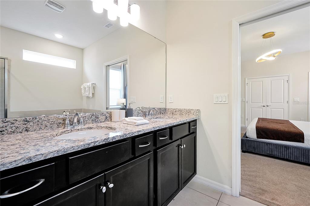 4494 Kaipo Road Davenport, FL 33897 - Photo 39 of 100 a bathroom with a granite countertop sink a mirror and a bathtub
