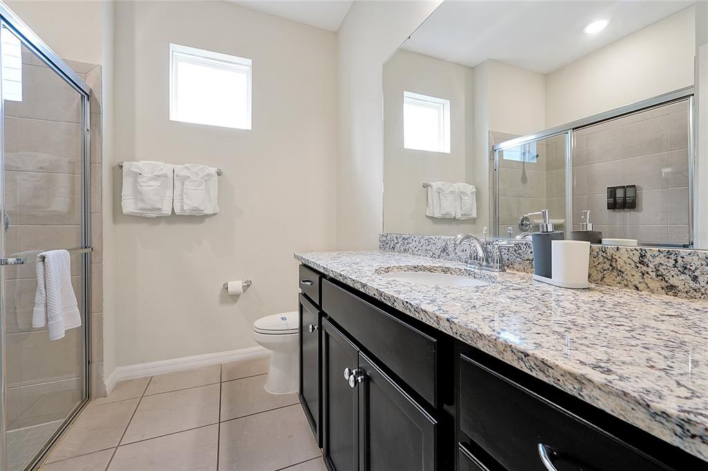 4494 Kaipo Road Davenport, FL 33897 - Photo 45 of 100 a bathroom with a granite countertop sink a toilet and mirror
