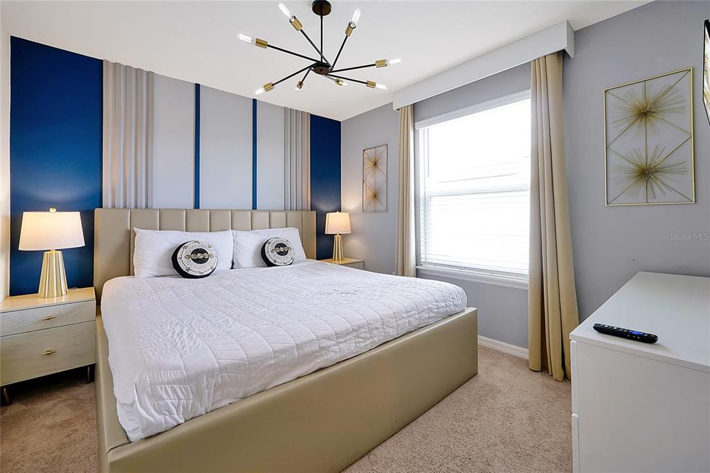 4494 Kaipo Road Davenport, FL 33897 - Photo 64 of 100 a bedroom with a bed and a chandelier