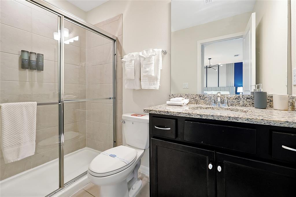4494 Kaipo Road Davenport, FL 33897 - Photo 67 of 100 a bathroom with a granite countertop sink toilet and shower