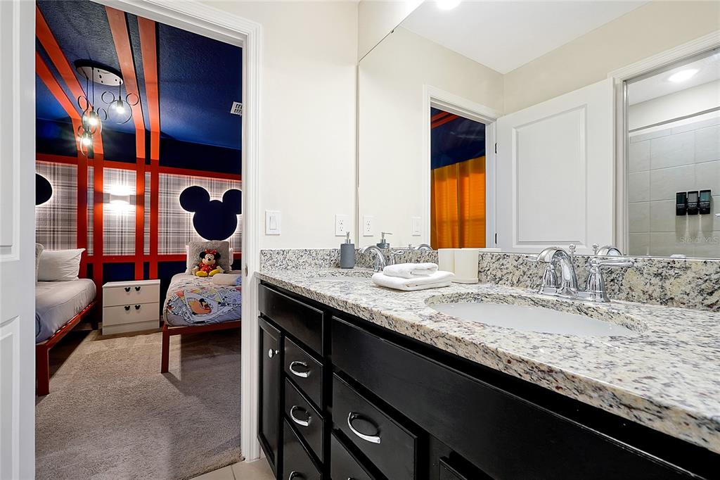 4494 Kaipo Road Davenport, FL 33897 - Photo 93 of 100 a en suite bathroom with a granite countertop sink and a mirror