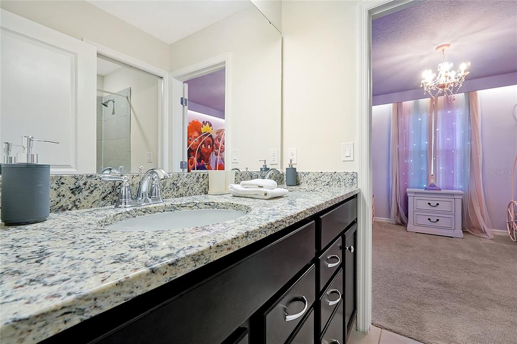 4494 Kaipo Road Davenport, FL 33897 - Photo 94 of 100 a bathroom with a granite countertop sink a mirror and a bathtub