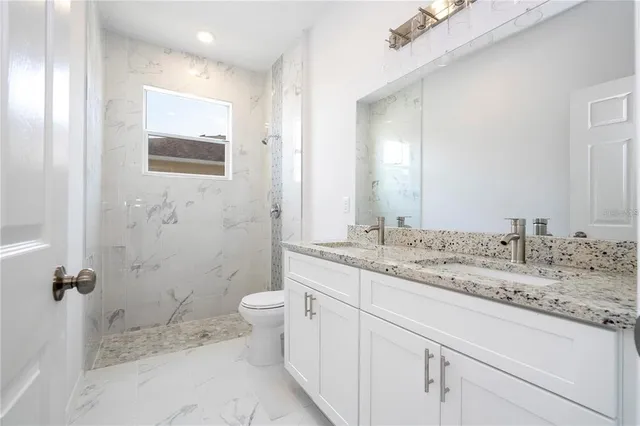 a bathroom with a granite countertop sink toilet and shower