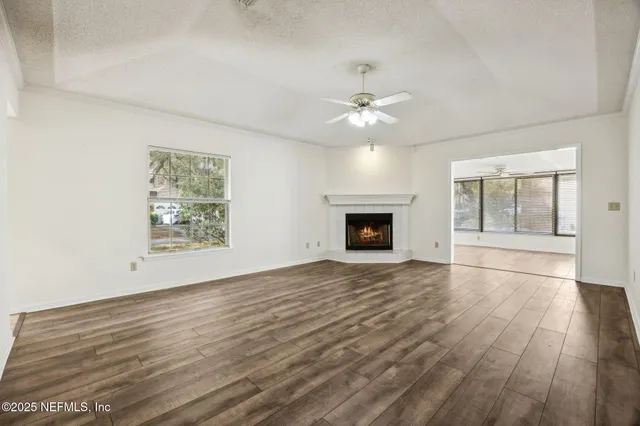 a view of an empty room with wooden floor and windows