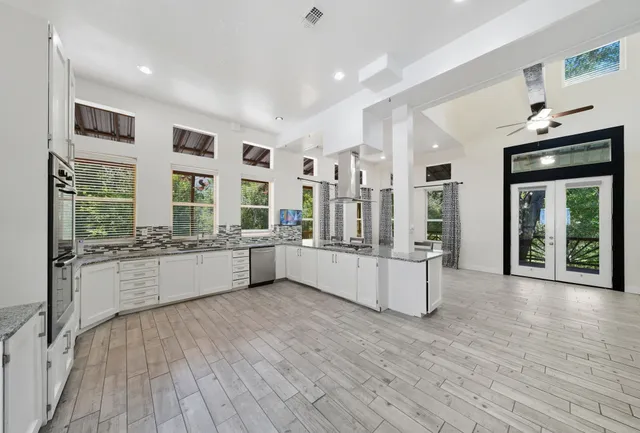 a large kitchen with stainless steel appliances wooden floor and a large window