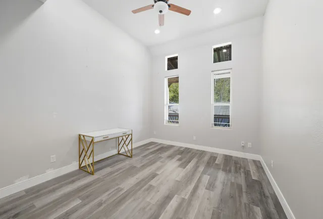 an empty room with windows and ceiling fan