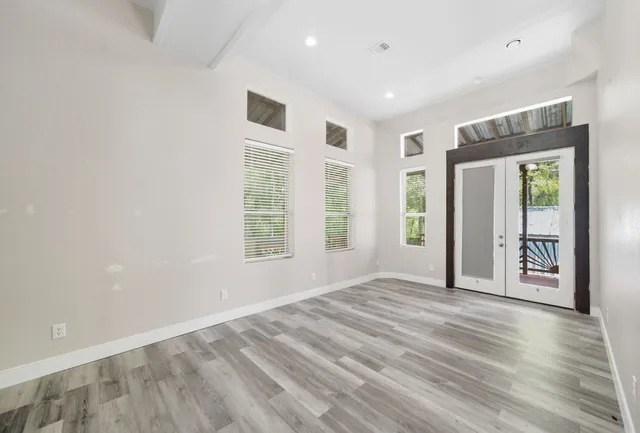 a view of an empty room with a window and wooden floor