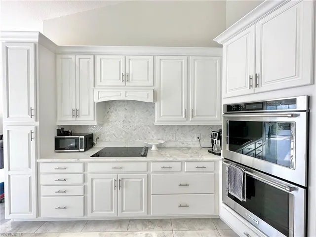 a large kitchen with kitchen island white cabinets and stainless steel appliances