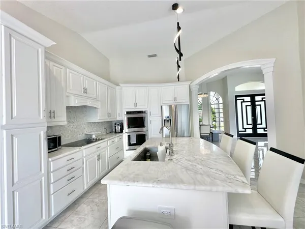 a kitchen with granite countertop a sink a counter top space appliances and cabinets