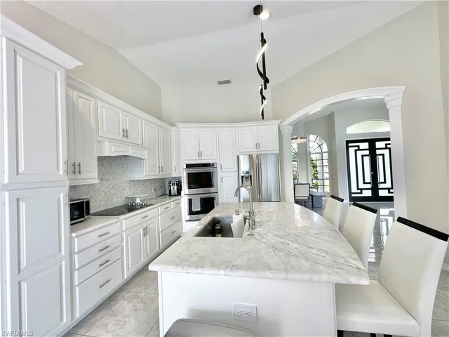 a kitchen with granite countertop a sink a counter top space appliances and cabinets