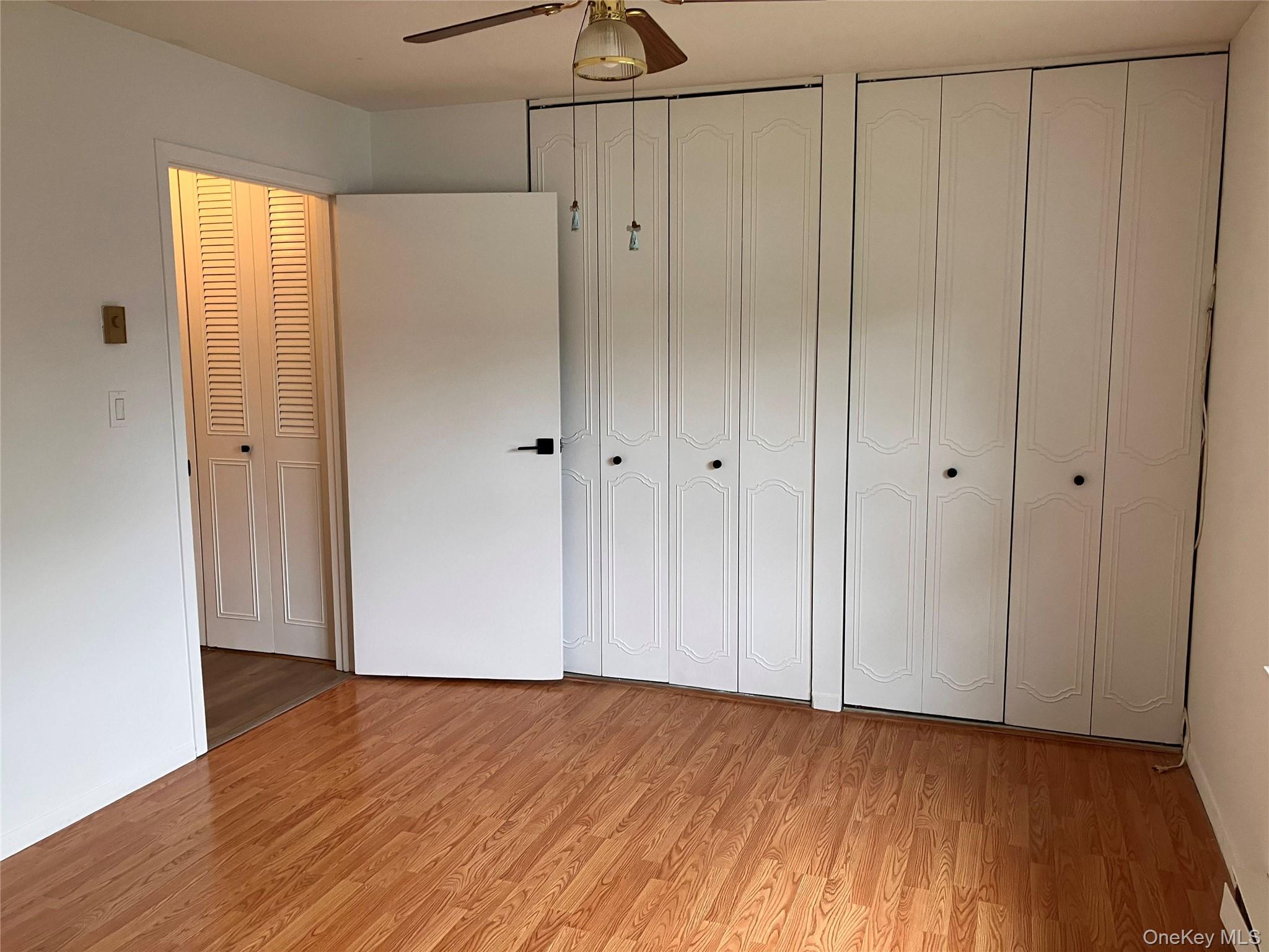 259 Newcastle Court, Unit E Ridge, NY 11961 - Photo 13 of 20 Unfurnished bedroom with light wood-type flooring, multiple closets, and ceiling fan