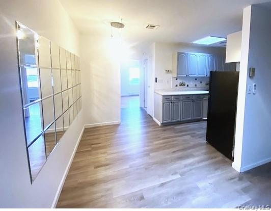 259 Newcastle Court, Unit E Ridge, NY 11961 - Photo 7 of 20 Kitchen featuring light countertops, freestanding refrigerator, dark wood-type flooring, tasteful backsplash, and pendant lighting