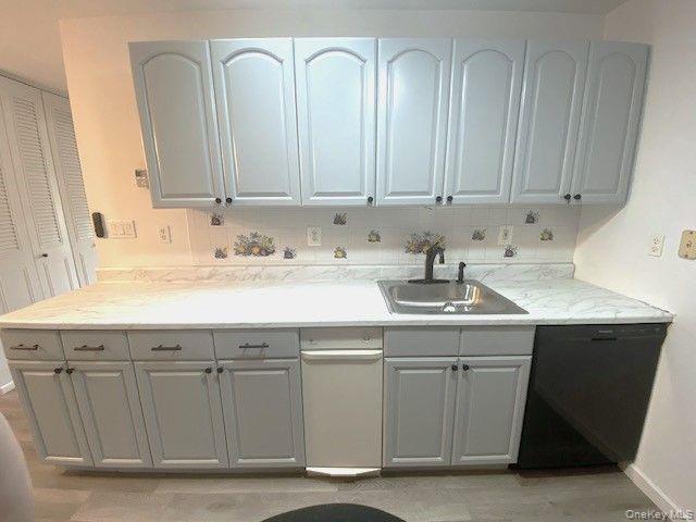 259 Newcastle Court, Unit E Ridge, NY 11961 - Photo 8 of 20 Kitchen with black dishwasher and gray cabinets