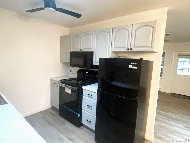 259 Newcastle Court, Unit E Ridge, NY 11961 - Photo 10 of 20 Kitchen with black appliances, light wood-style floors, ceiling fan, and light countertops