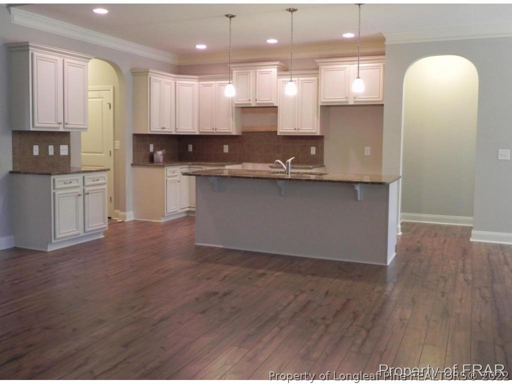 1280 Rays Bridge Road Whispering Pines, NC 28327 - Photo 8 of 22 a open kitchen with kitchen island a sink dishwasher stove and wooden floors