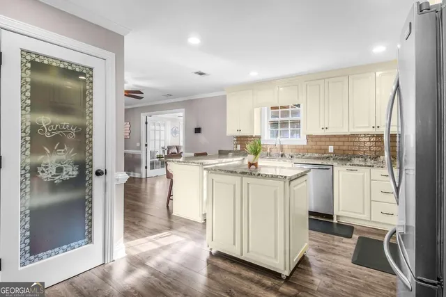 a kitchen with kitchen island white cabinets appliances and a window