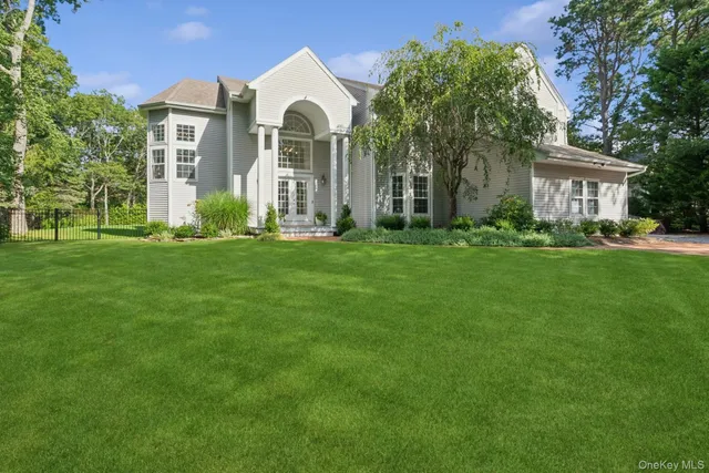 a view of a house with a big yard and large trees