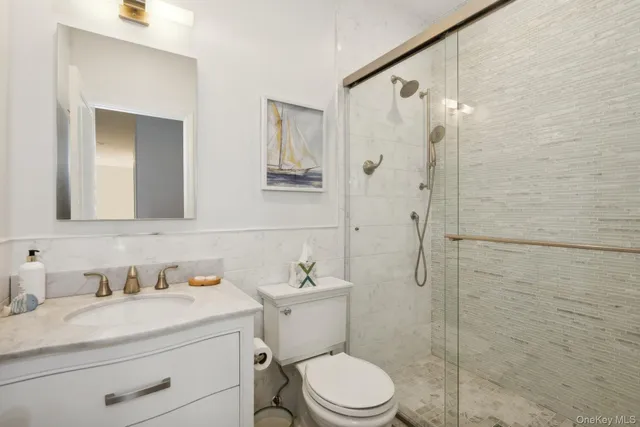a bathroom with a granite countertop sink toilet a mirror a shower and vanity