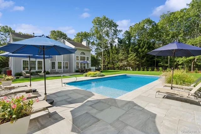 a view of a swimming pool with a table and chairs under an umbrella