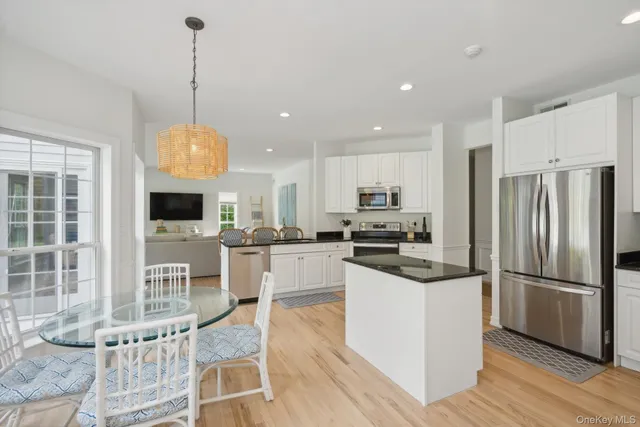 a kitchen with stainless steel appliances granite countertop a refrigerator a stove a sink dishwasher a refrigerator and a dining table with wooden floor
