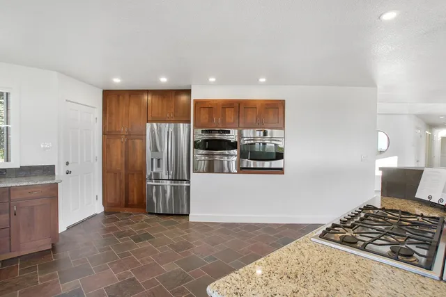 a kitchen with stainless steel appliances granite countertop a refrigerator and a stove top oven