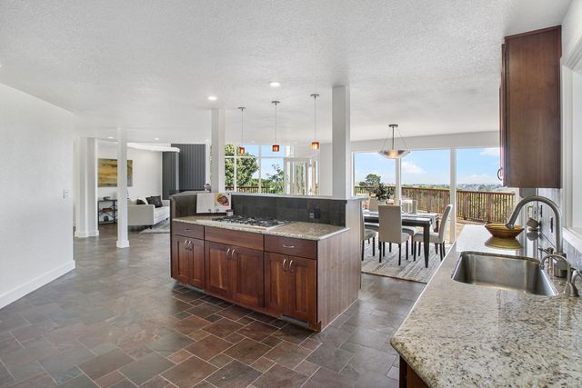 a kitchen with stainless steel appliances granite countertop a sink a stove and a dining table