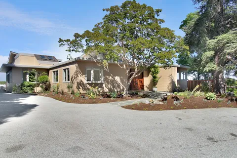 a view of a house with large trees and plants
